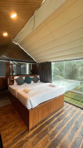 a large bed in a room with a large window at Nyast Valley Resort by Autumleafs, Goa in Arpora
