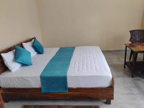- une chambre avec un lit doté d'oreillers bleus et d'une table dans l'établissement Tathastu Resort Tehri By Royal Collection Hotels, à Tehri-Garhwāl