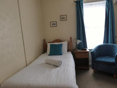 a bedroom with a bed and a chair and a window at The Denewood in Sandown