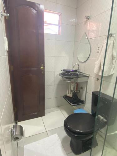 a bathroom with a black toilet and a mirror at Quarto do junior in Belém