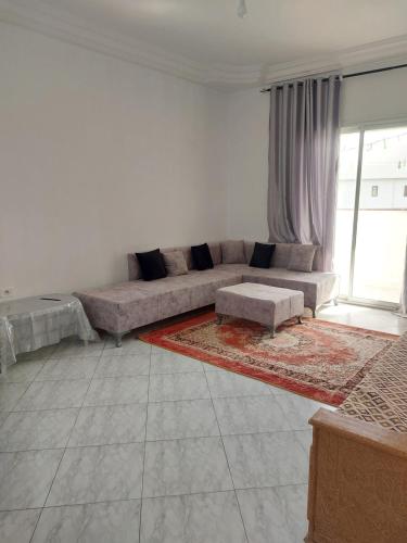 een woonkamer met een bank en een groot raam bij Location saisonnière entre mer, forêt et calme in Raʼs al Jabal