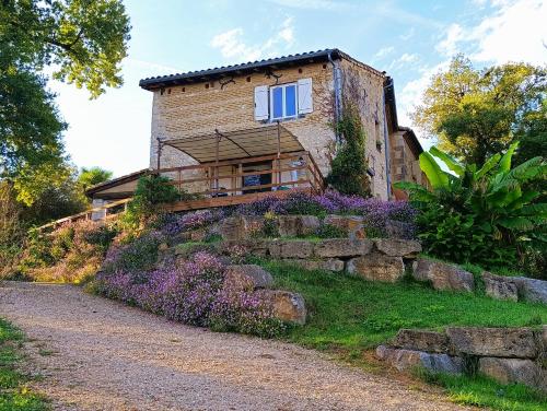 una casa en una colina con flores púrpuras delante en Castel Mazars, en Castelnau-de-Montmiral