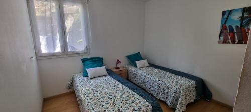 two beds in a room with a window at La Kaz Bellepierre in Saint-Denis