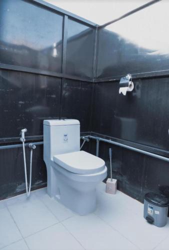 a bathroom with a toilet and a black wall at Star line for Desert Camping in Badīyah