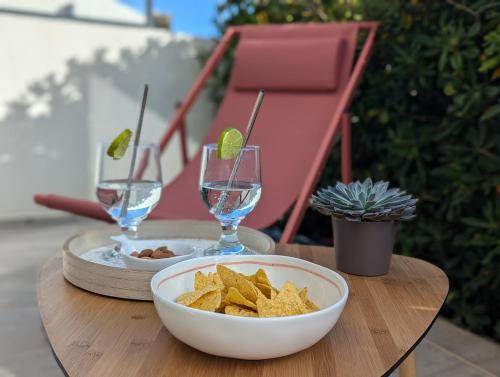 a table with a bowl of chips and glasses of wine at Côté Phares, 4 étoiles, appartement 43 m2 Vue Mer in Les Sables-dʼOlonne