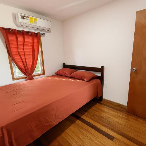 a bedroom with a bed with a red bedspread and a window at Lily's Sunrise Villa in Ladyville