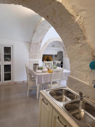 eine Küche mit einem Waschbecken und einem Tisch in der Unterkunft Trullo il Gelso with Private Salt Water Infinity Pool and Jacuzzi inside in San Michele Salentino