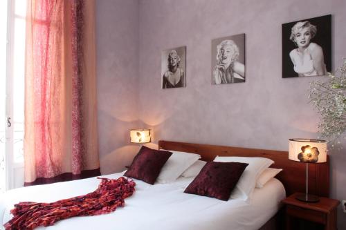 a bedroom with a white bed with three pictures on the wall at Le Panoramic Boutique Hôtel in Nice