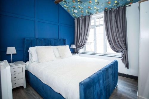 a blue bedroom with a large bed and a window at The Coach House by The Hive WA1 in Warrington