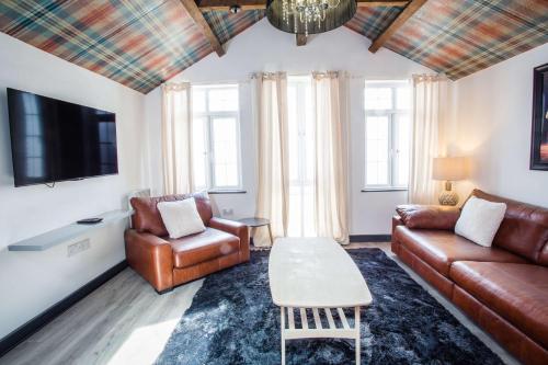 a living room with a couch and chairs and a tv at The Coach House by The Hive WA1 in Warrington