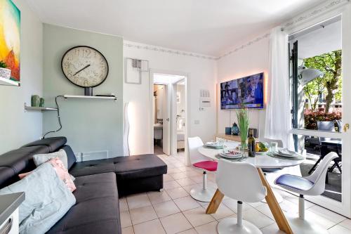 ein Wohnzimmer mit einer Couch und einer Uhr an der Wand in der Unterkunft Budget Village Apartments - Porto Letizia in Porlezza