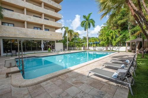 a swimming pool in front of a building with palm trees at Regency Miami Airport by Sonesta in Miami