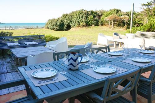 a blue table with plates and wine glasses on it at Villa Rétaise face mer - Sainte-Marie-de-Ré in Sainte-Marie-de-Ré
