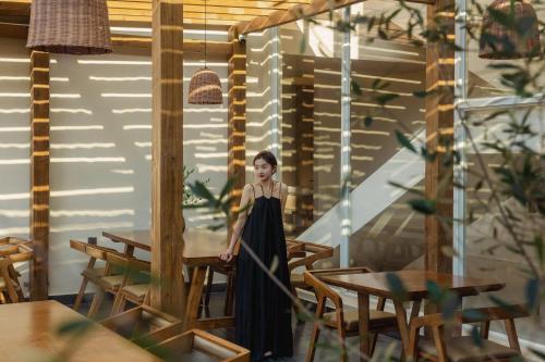 Dali AirportにあるDali Antu Yuanchu seaview Homestayのテーブルのある部屋に立っている黒いドレスを着た女性