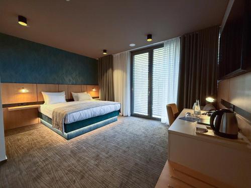 DobovaにあるTerme Paradiso - Hotel Paradisoのベッドと大きな窓があるホテルの部屋
