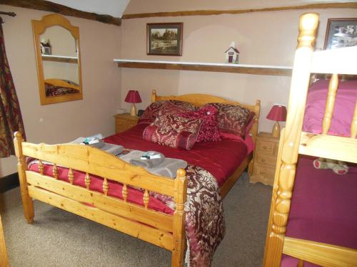 1 dormitorio con cama de madera con sábanas rojas en Lower Lode Inn, en Tewkesbury