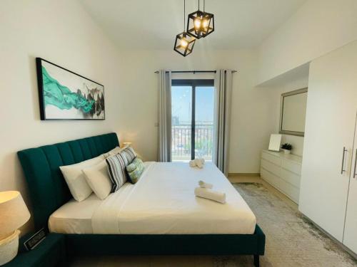 Nadd ShubayḩにあるTown Square Zahra 2B - 2 Bedroom Apartment - Allsopp & Allsoppのベッドルーム(大型ベッド1台、緑のソファ付)