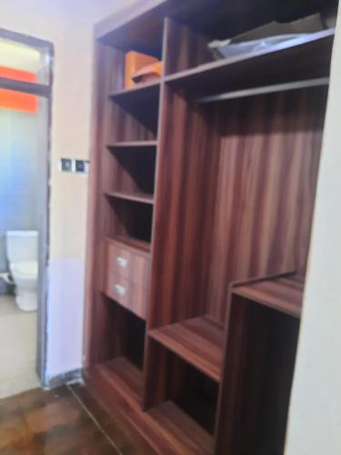 a wooden book shelf in a room with a toilet at Cobbs in Nanyuki