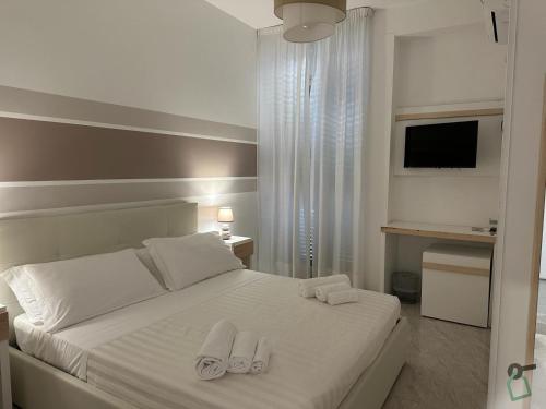 a bedroom with a white bed with towels on it at Hotiday Porto Cesareo in Porto Cesareo