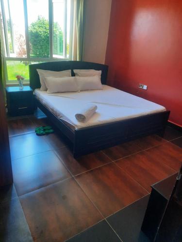 a bedroom with a bed with white sheets and pillows at Cobbs in Nanyuki