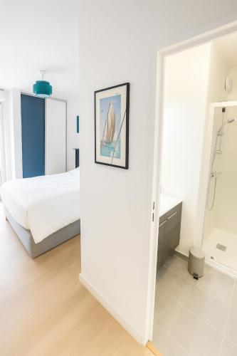 a white bedroom with a bed and a mirror at Balcon sur docks - 4 lits - 4 beds in Le Havre