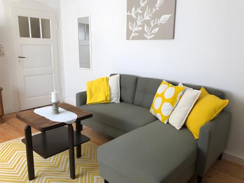 a living room with a gray couch and yellow pillows at Mein Ferienhaus Rosenbusch 1 in Kemmern