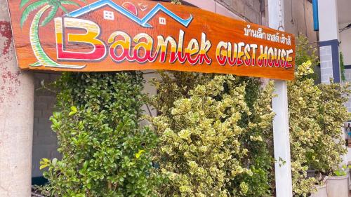a sign on the side of a building with plants at Baanlek Guest House in Ko Lanta