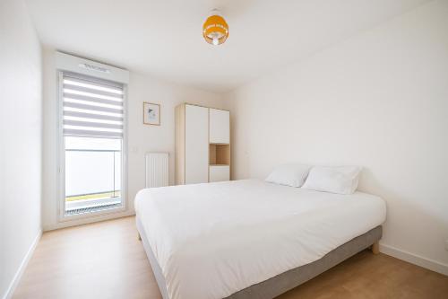 a white bedroom with a large bed and a window at Balcon sur docks - 4 lits - 4 beds in Le Havre
