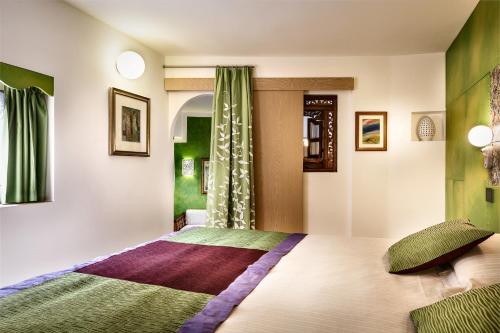 a bedroom with a large bed with green and purple at Hotel Stella Maris in Villasimius