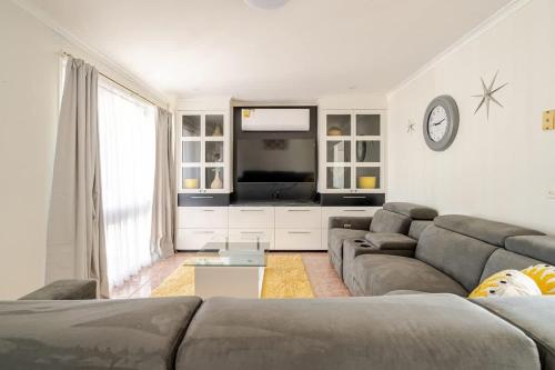 a living room with a couch and a flat screen tv at Beautiful and Colourful House with Parking in Rooty Hill