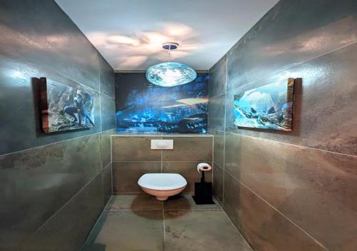 Un baño con inodoro y cuadros en la pared. en The Art of Disney Chessy, en Chessy