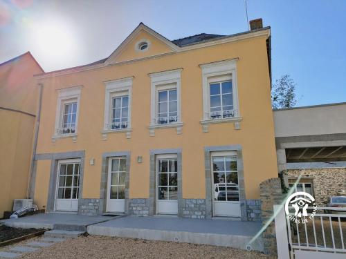 une maison jaune avec des fenêtres blanches dans l'établissement Gîte Le 47, 6 à 8 personnes, à Louverné