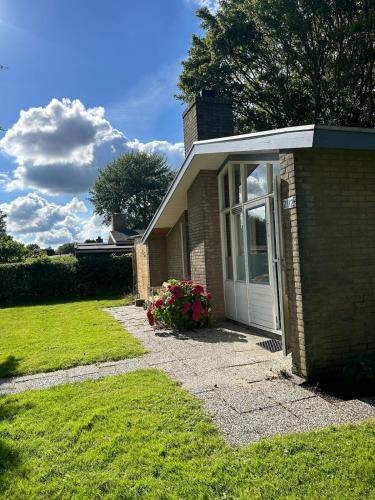 een klein bakstenen huis met een deur en bloemen bij Bungalow Het Grootslag in Andijk