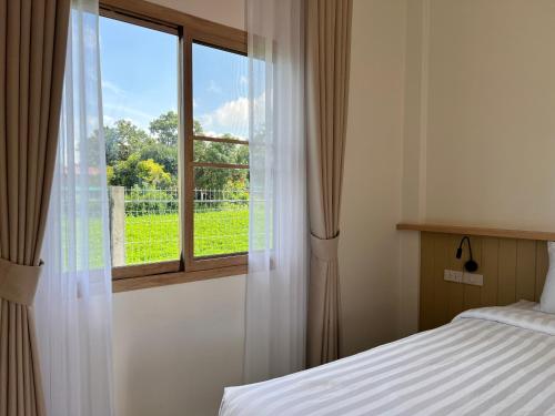 een slaapkamer met een bed en een raam bij เดอะริม รีสอร์ท The Rim Resort in Ban Muang