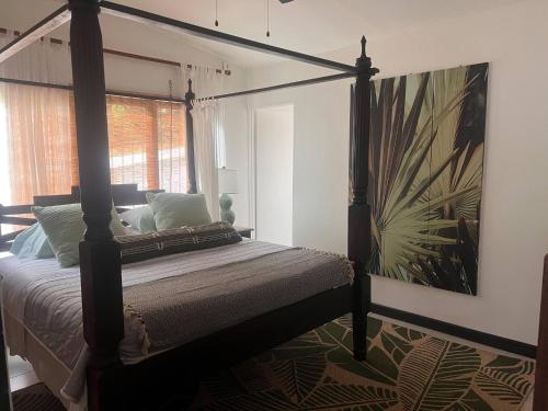 a bedroom with a four poster bed with a painting on the wall at Beachfront Paradise in Tivives, Costa Rica - Your Home Away from Home in Corralillo