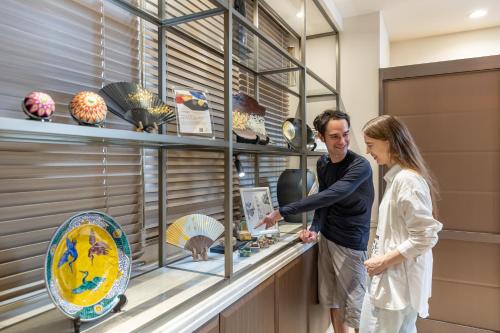 a man and a woman looking at a display case at HOTEL MYSTAYS Kanazawa Katamachi in Kanazawa