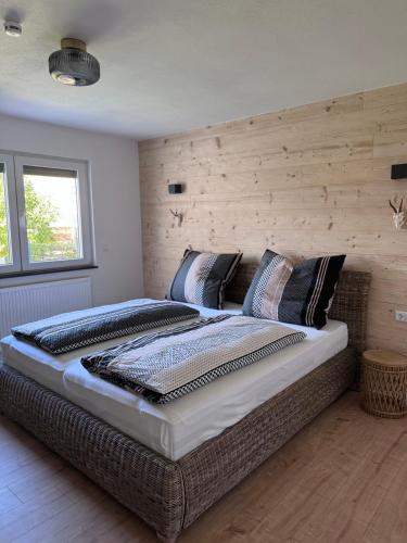 a large bed in a bedroom with a wooden wall at Unger's Ferienwohnung Mariella in Isny im Allgäu