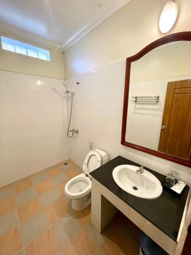 a bathroom with a toilet and a sink and a mirror at You Mean Heng Guesthouse in Kampot