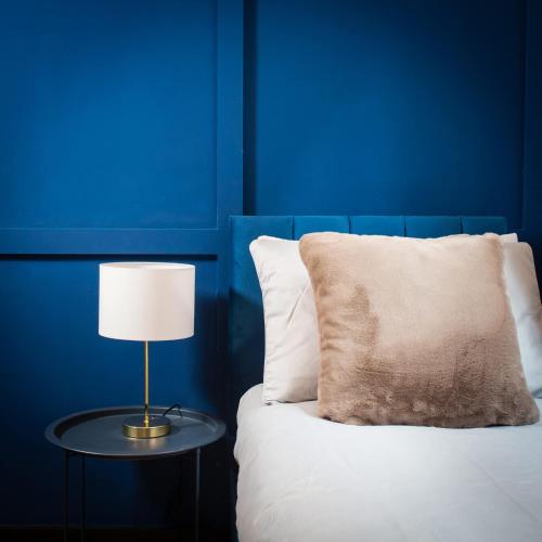 a bed with a table with a pillow and a lamp at The Warldorf, King Size and Twin Apartment by The Hive WA1 in Warrington