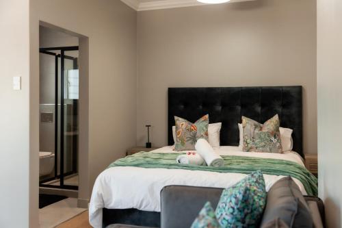 a bedroom with a large bed with a black headboard at Walton Cottages of Mill Park, Port Elizabeth in Port Elizabeth