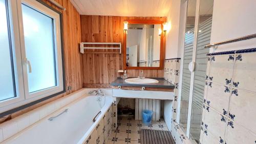 un bagno con vasca, lavandino e specchio di Charmante villa au centre de la Couarde avec cour a La Couarde-sur-Mer