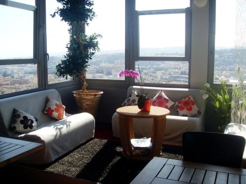 a living room with a couch and a table and windows at Le Panoramic Boutique Hôtel in Nice