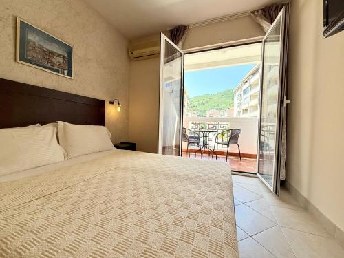 a bedroom with a bed and a view of a balcony at Budva Perla di Mare Hotel in Budva