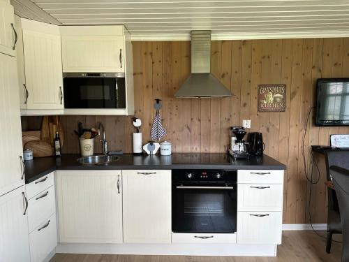 a kitchen with white cabinets and a black stove top oven at Koselig vestlandshus ved fjorden in Holmedal