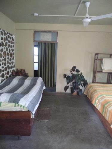 a bedroom with two beds and a potted plant at Upavan Homestay in Lataguri