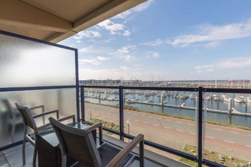 エイマイデンにあるLeonardo Hotel IJmuiden Seaport Beachの港の景色を望むバルコニー(椅子付)