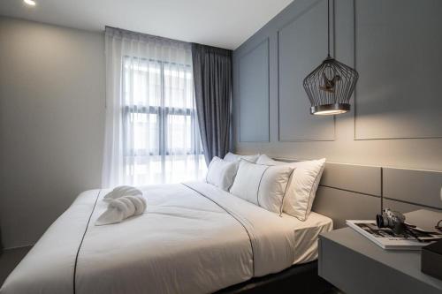 ein Schlafzimmer mit einem weißen Bett mit einem Fenster in der Unterkunft Palmyrah Surin Apartments, Phuket, by the Sea in Ban Lum Fuang