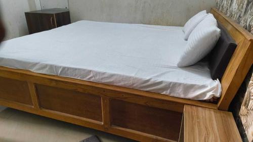 a wooden bed with white sheets and pillows on it at Hotel O Bihar Sharif Railway Junction Formerly Shree Balajee in Bihār Sharīf