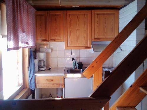 nad głową małą kuchnię z drewnianymi szafkami w obiekcie Vuokatti Cottages w mieście Vuokatti