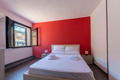 una camera da letto con una parete rossa e un letto di White Lion SURF & MINE GUESTHOUSE a Buggerru